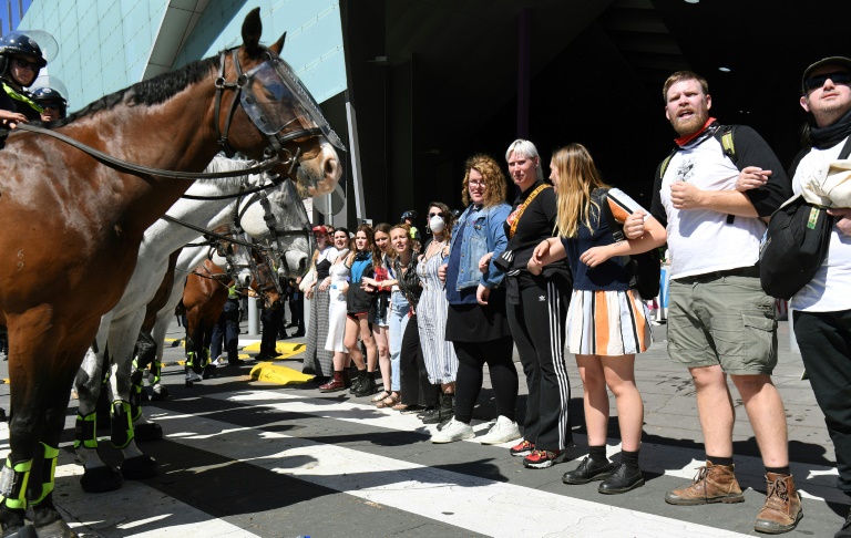 Climate change protesters attempting to blockade a mining conference linked arms in front of mounted police in Melbourne before clashes started | © AFP | William WEST